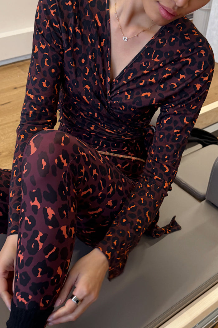 Dark Leopard Leggings and matching wrap top with contrast orange detailing, shown in a gym setting.