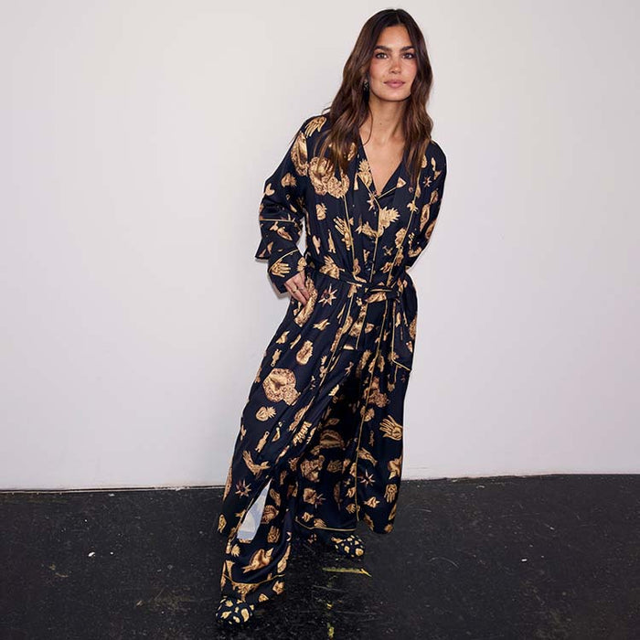 Black Deloris Satin Robe with gold hand and eye motifs, featuring a waist tie and styled with matching pyjamas.