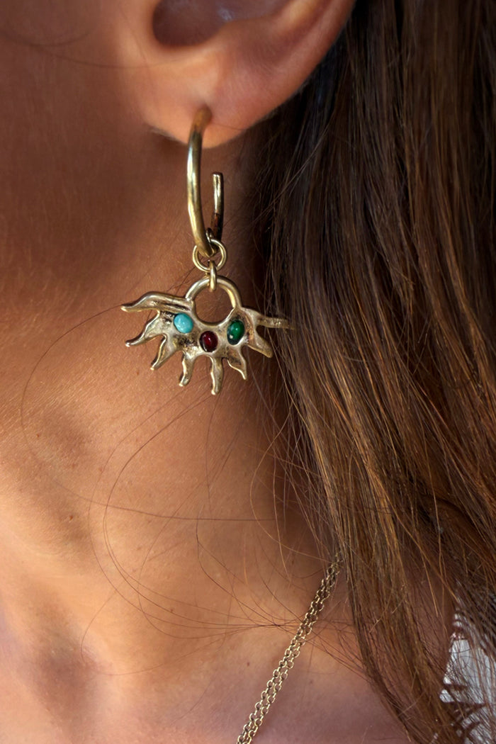 Gold-tone Deloris Sun Hoop Earrings featuring iconic sun motifs and semi-precious stones, worn on the ear.