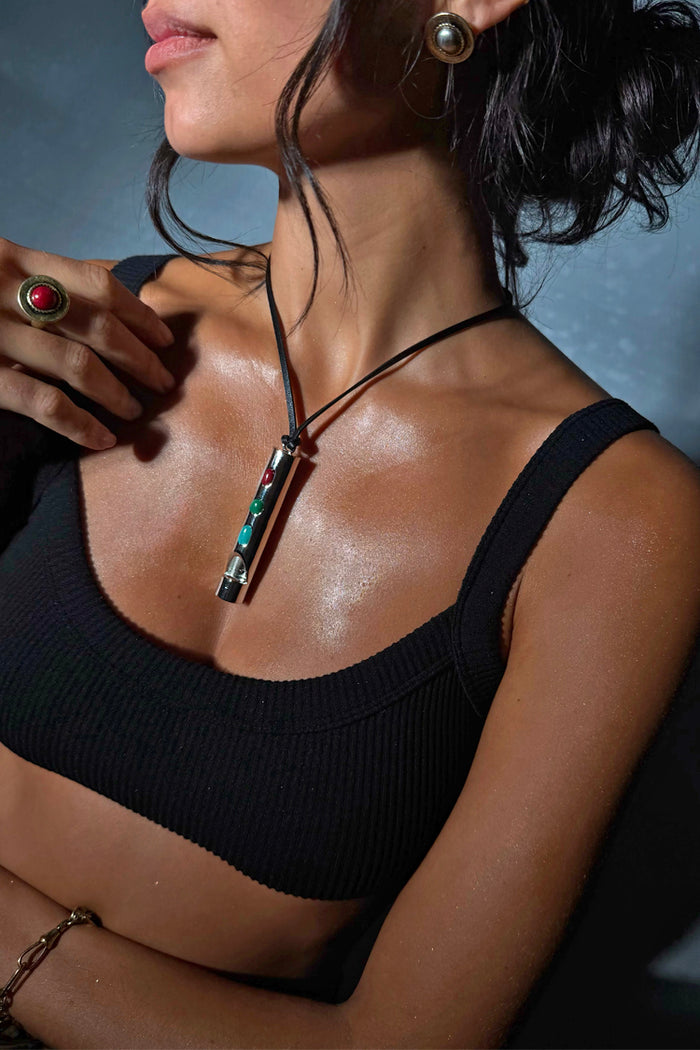 Deloris Whistle Necklace with a polished silver-tone pendant and colourful gemstones on a black leather cord.
