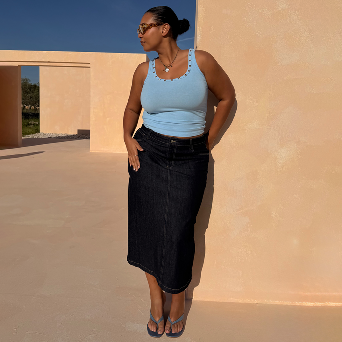 Dark blue midi Denim Pencil Skirt in inclusive sizing, styled with a light blue ribbed vest top and sandals.