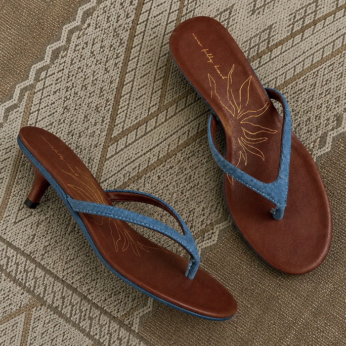 Denim Sandal Mules featuring slim blue straps, a low sculpted kitten heel, and brown cushioned soles with a sun motif.