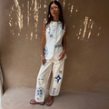 Cream Dolce Vita embroidered denim barrel leg jeans with blue motifs, worn with a matching waistcoat.