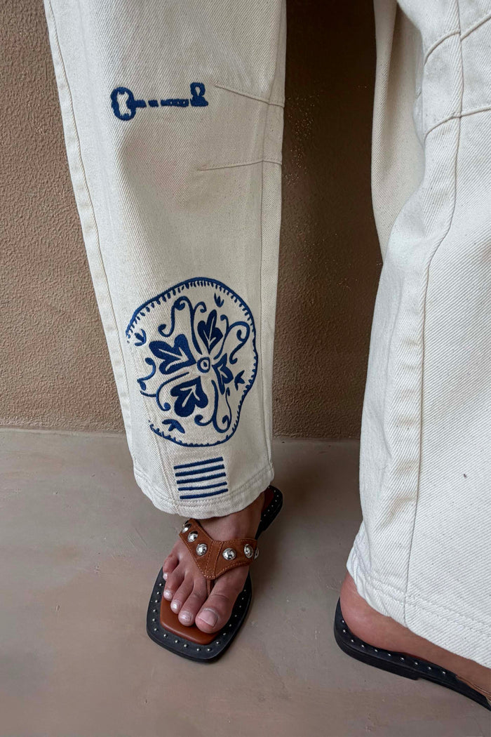 NFD Dolce Vita Cream Denim Barrel Leg Jeans featuring blue Greek-inspired embroidery on the hem.