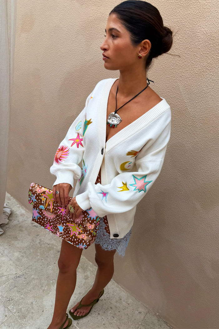 Cream Dreamer Martha Cardigan in soft-touch knit with sun and star motifs, styled with a patterned clutch bag.