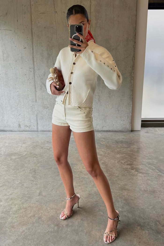 Ecru Studded Hot Pant in cream cotton with silver studs, paired with a matching jacket and heels.