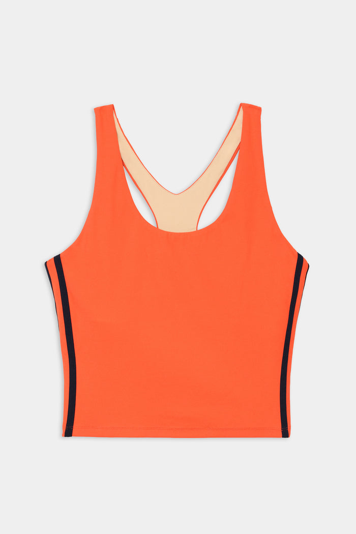The SPLITS59 Ella Airweight Tank in Valencia/Indigo is an orange athletic crop top with a scoop neck, racerback, and indigo vertical side stripes. Made from stretch fabric, it provides comfort and flexibility for workouts.