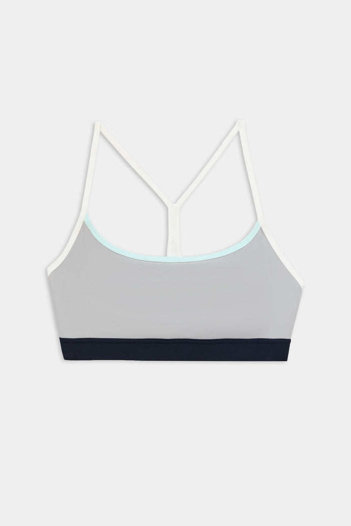 The SPLITS59 Emerson Airweight Bra in Dove Grey/Indigo features thin white straps, a light blue neckline trim, and a black elastic band—ideal for hot yoga or Pilates.