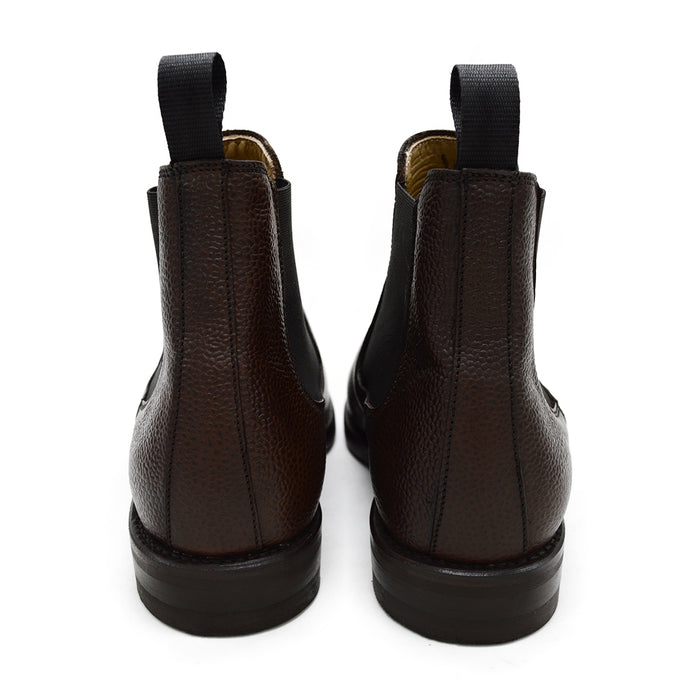 A dark brown grain leather Chelsea boot with a black elastic side panel and a round toe. The boot has a low heel and a goodyear welted dainite rubber sole.