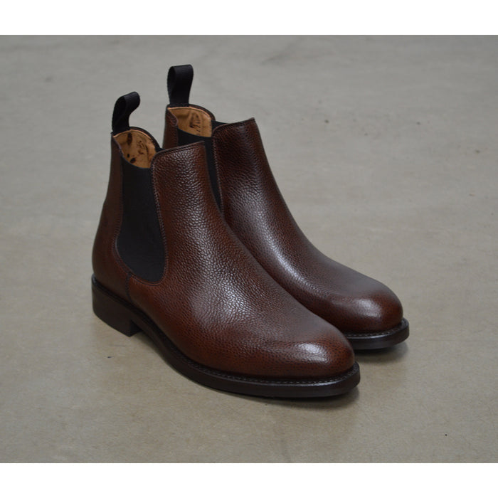 A dark brown grain leather Chelsea boot with a black elastic side panel and a round toe. The boot has a low heel and a goodyear welted dainite rubber sole.