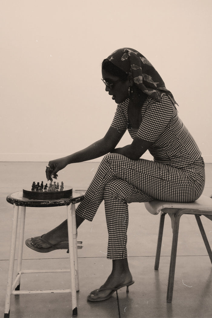 Gingham Trousers and top co-ord styled with a fish-print headscarf, shown on a model playing chess.