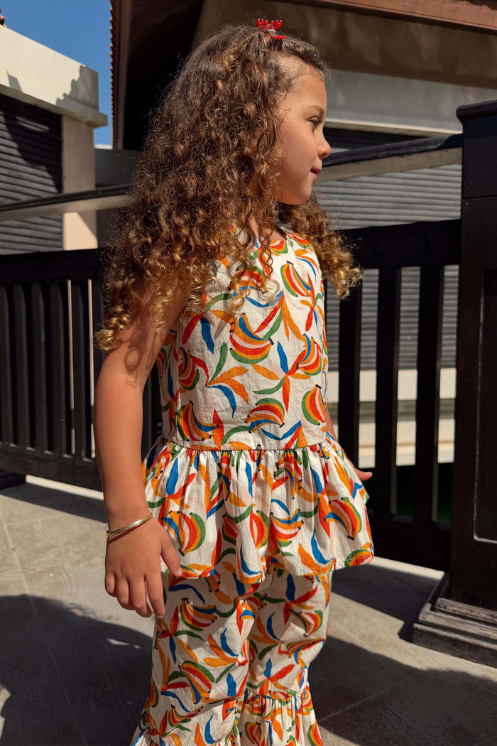 Girl's Banana Cotton Woven Set in a multicoloured banana print, with a sleeveless peplum top and flared trousers.