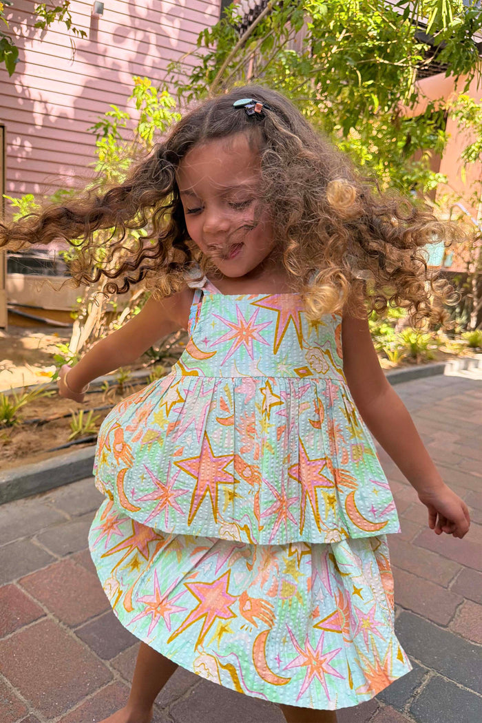 Blue Starburst Skirt Co-ord Set featuring a sun and star print peplum top and tiered cotton skirt on a young girl.