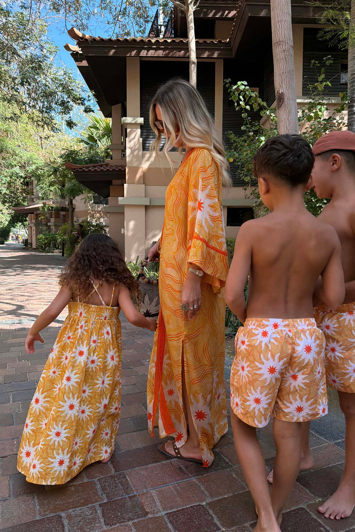 Yellow cotton girl's sun dress with a sun print and shirred top, part of a matching family vacation outfit.