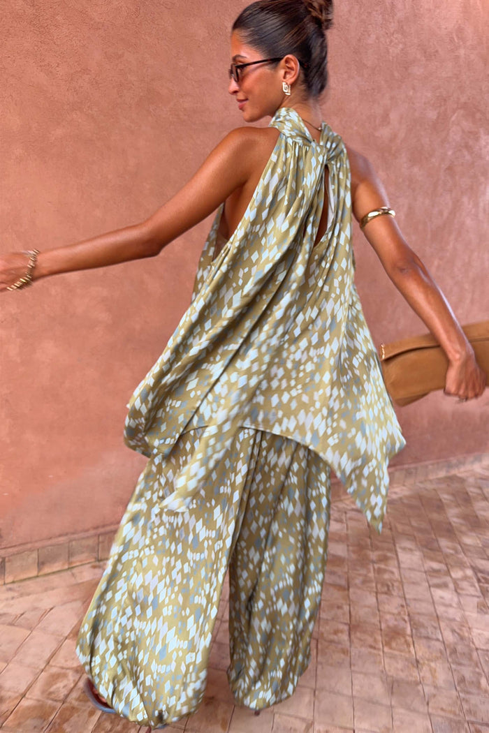 Olive green diamond print halter top with a draped back and asymmetric hem, styled with matching co-ord trousers.