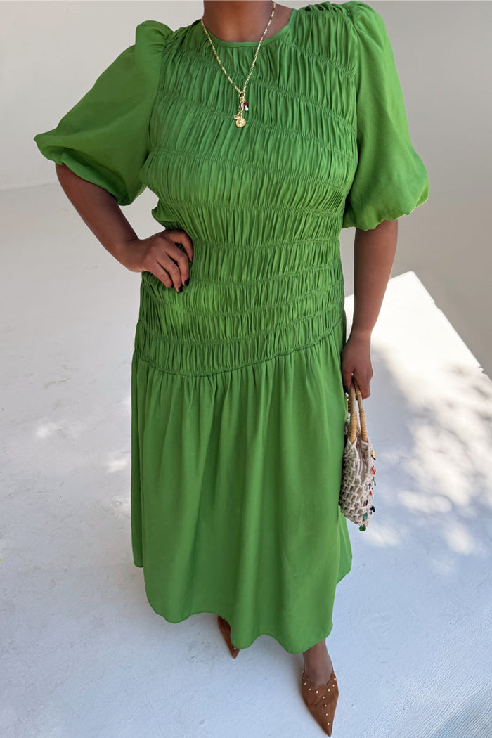 Green Shirred Nara Dress featuring a smocked bodice and puff sleeves, shown on a model for inclusive sizing.