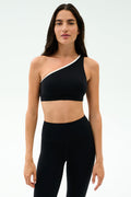 Person standing against a plain background, wearing the SPLITS59 Josie Airweight One Shoulder Bra in Black/White and high-waisted black leggings—perfect for hot yoga sessions.