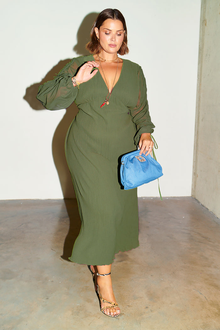 Khaki Celia Plisse Dress with long sheer sleeves and v neck, styled with a blue clutch and leopard print heels.