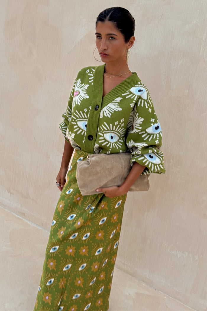 Khaki Eye Dorris Skirt with mystical eye and heart prints, styled with a matching cardigan and oversized beige clutch.