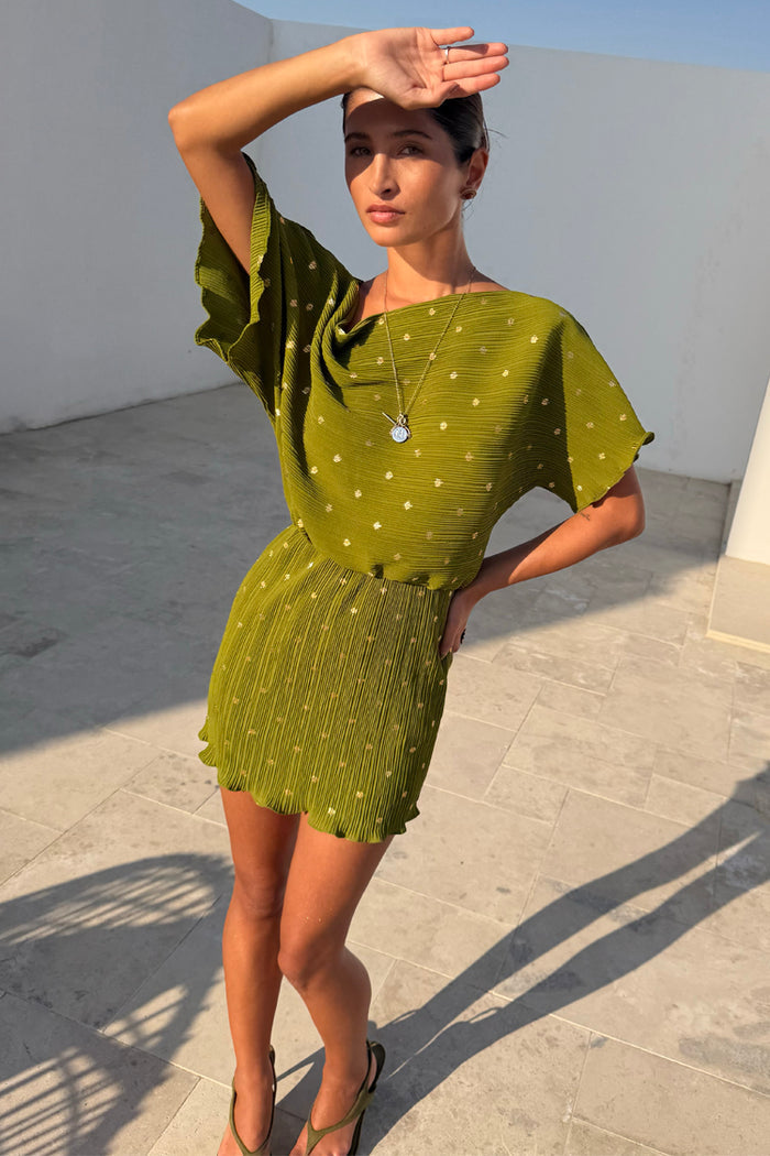 Khaki Mini Plisse Tilly Dress featuring a gold fleck print and wide sleeves on a model in a sunny outdoor setting.