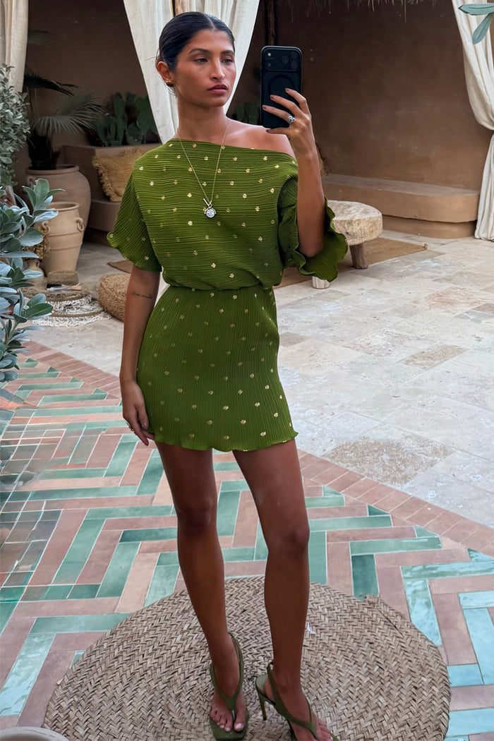 Khaki Mini Plisse Tilly Dress featuring gold fleck print and an elasticated waist, styled for a chic holiday look.