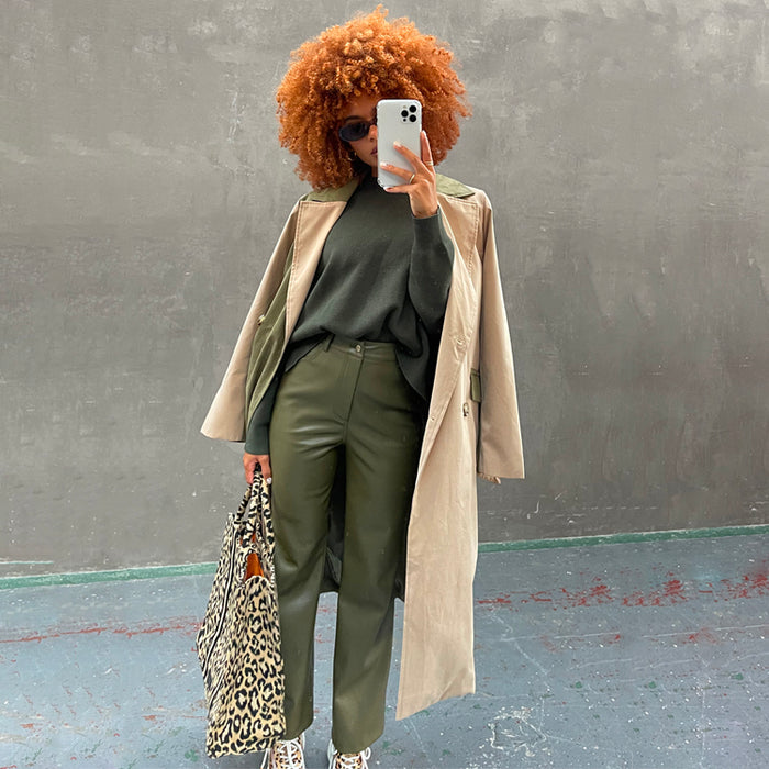 Khaki Vegan Leather Trousers styled with a green knit, beige trench coat, and leopard print tote bag.