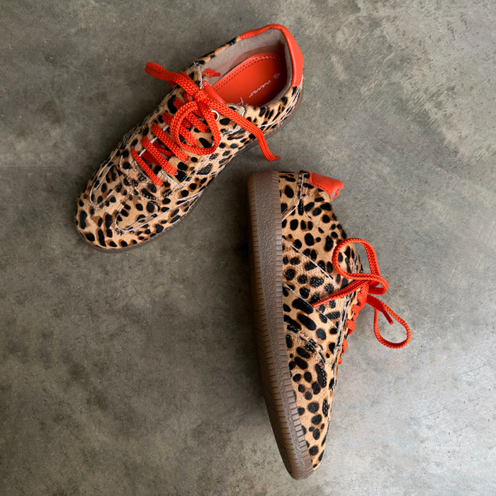 Leopard Pony Trainer in iconic leopard print leather with contrast orange laces and a gum sole on a grey floor.