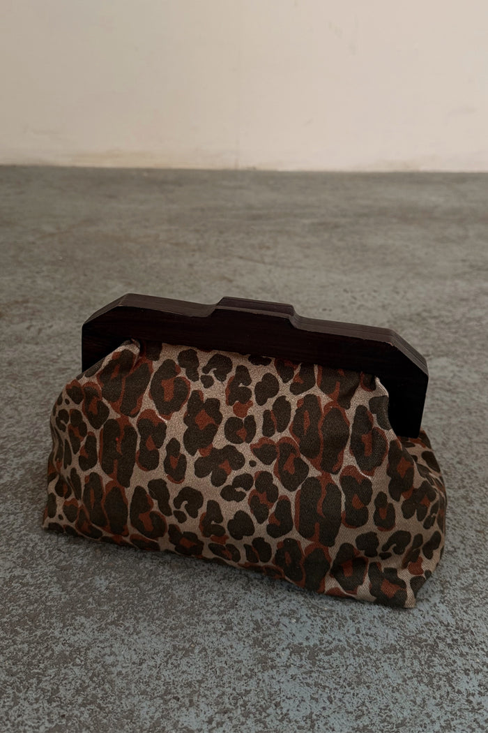 Lucia Leopard Denim Bag with an iconic leopard print and dark wooden handle, shown on a textured grey floor.