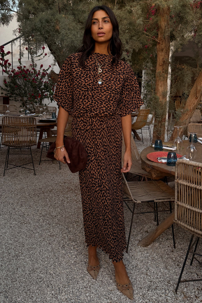 Lucia Leopard Tilly Dress in plisse fabric with an iconic leopard print and elasticated waist at a restaurant.