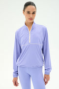 A woman wears the SPLITS59 Lyle Woven Nylon Pullover in Purple Haze/Creme, standing against a plain white background.
