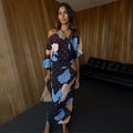 Mara Abstract Tilly Dress featuring a brown abstract print with gold metallic flecks and a voluminous one-shoulder top.