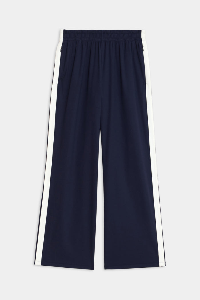 Maxie Rigor Track Pant by SPLITS59, featuring a navy color with an elastic waistband and white side stripes, showcased on a plain background.