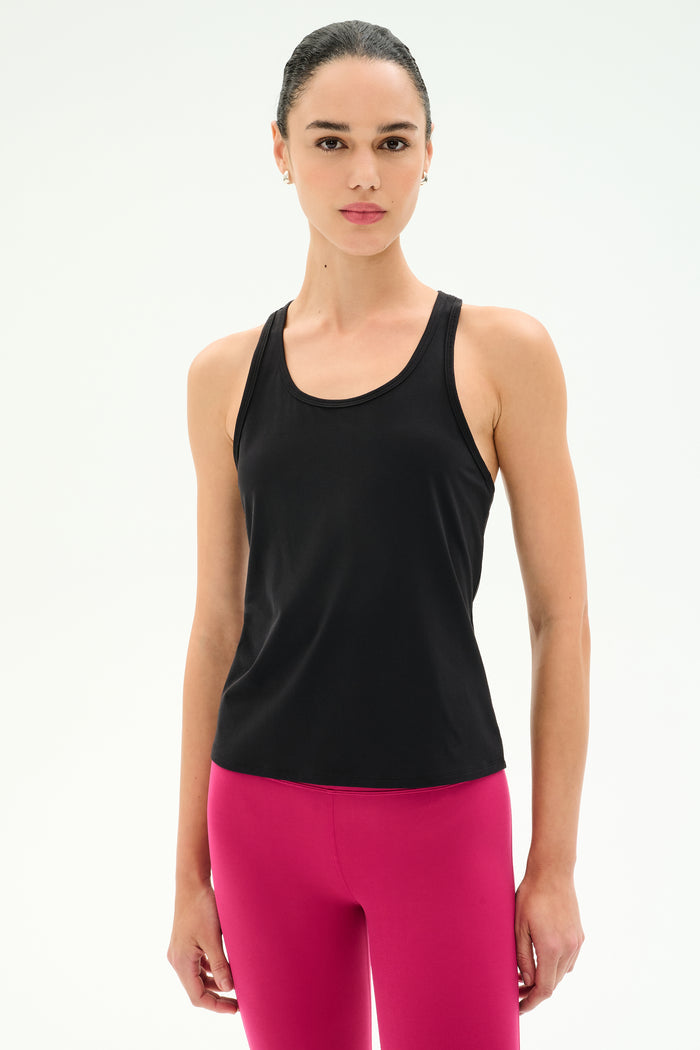 A woman faces forward in the SPLITS59 Mel Airweight Lite Tank - Black and bright pink leggings, ideal for hot yoga or Pilates, against a plain white background.