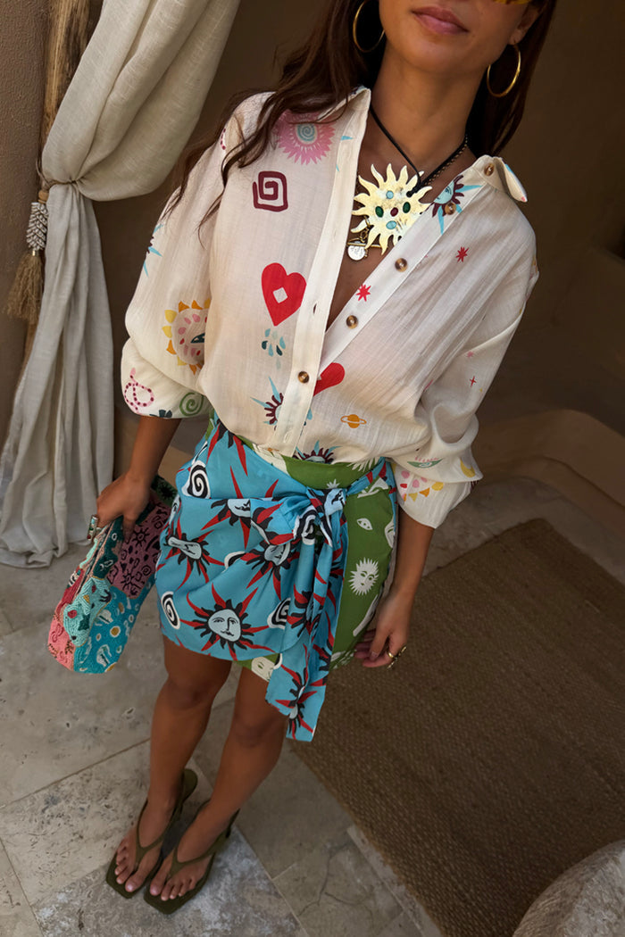 Multi-wear Morocco Mini Wrap Skirt with blue and green sun prints and side-tie fastening, perfect for dopamine dressing.