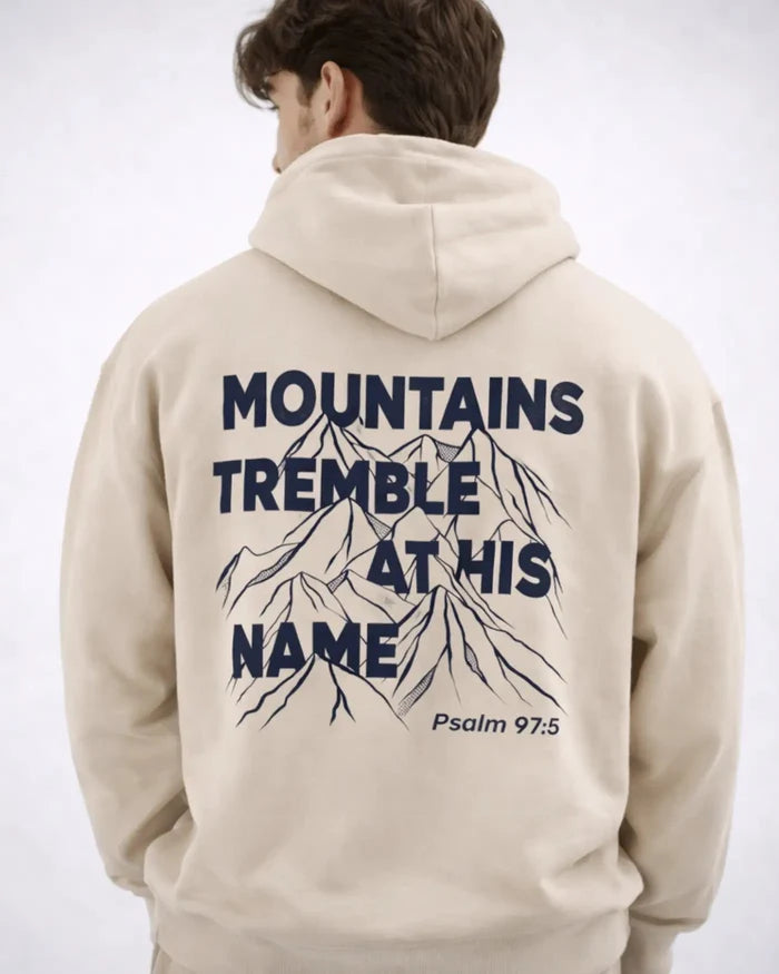 Beige hoodie with mountain graphic and text on the back, worn by a person.