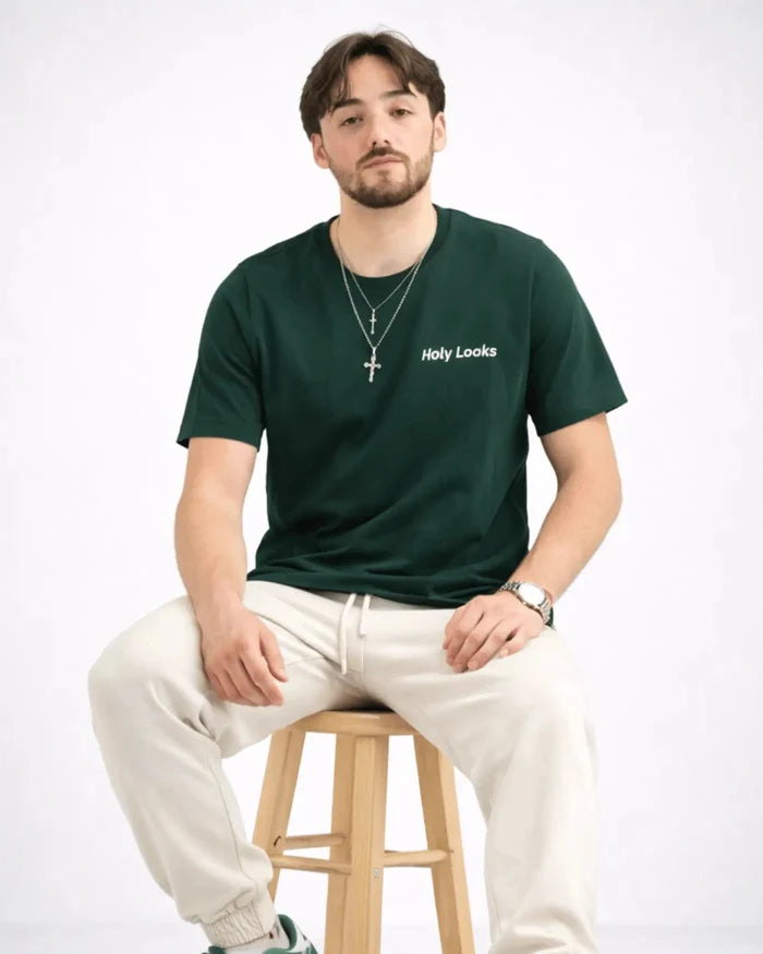 Man sitting on a stool wearing a green t-shirt with 'Holy Looks' text.