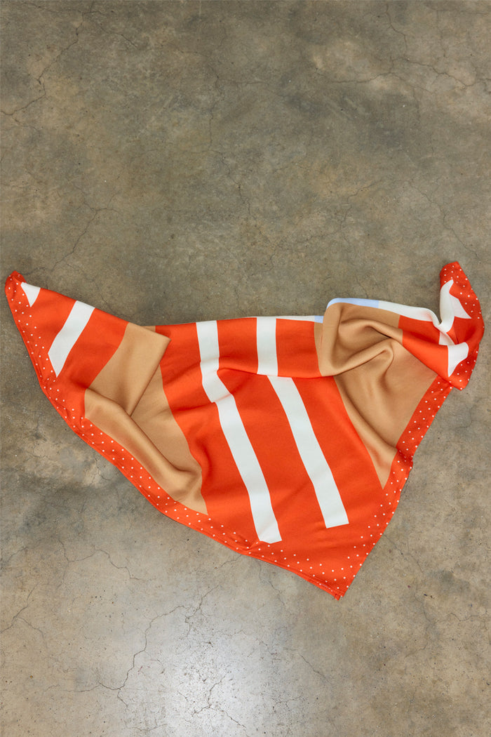 Multi Stripe Mix Bandana featuring orange, tan and white stripes and a polka dot border, displayed on a concrete floor.