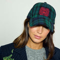 Navy Tartan NFD Cap in a blue and green cotton check with a red embroidered logo, styled on a model in a pinstripe blazer.