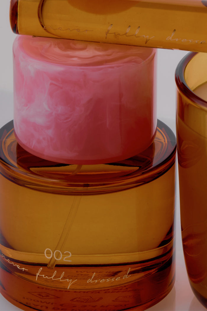 NFD Eau De Parfum 002 in an amber glass bottle with a marbled pink cap and gold script branding.