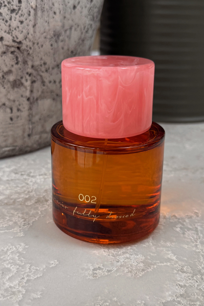 NFD Eau De Parfum 002 bottle with amber-toned glass, a pink marbled cap, and gold script logo.
