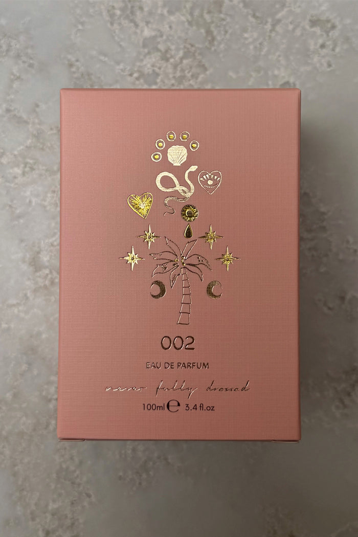 NFD Eau De Parfum 002 in a pink textured box with gold foil palm tree and celestial illustrations.