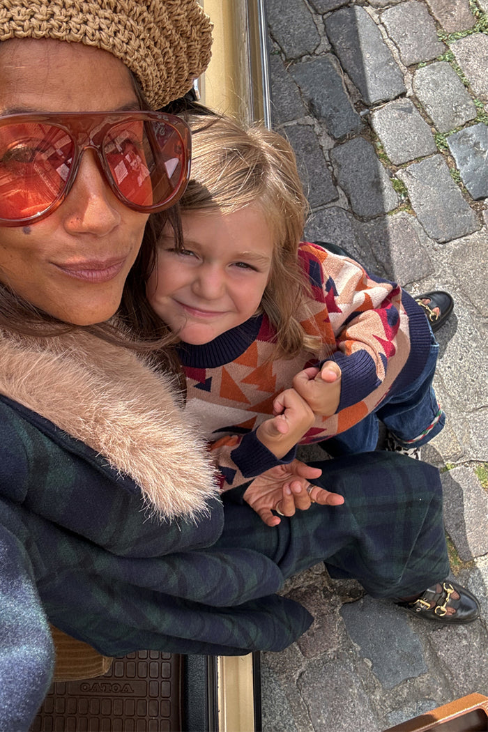 NFD Kids Aspen Jumper with a geometric orange and navy knit pattern worn by a child in a street style setting.