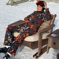 Night Garden Ski Suit featuring leopard and poppy prints, worn by a woman lounging at a snowy ski resort.