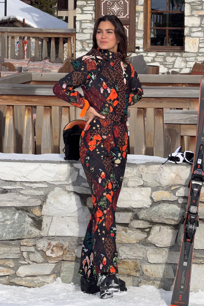 Night Garden Ski Suit featuring iconic leopard and poppy prints, styled on a model in a snowy resort.