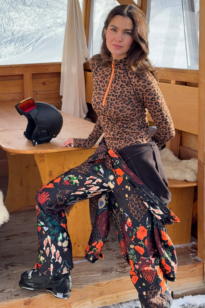 Night Garden Ski Suit featuring leopard and poppy prints, worn by a 5ft7” model in a UK size 10/ US 6 in a wooden chalet.