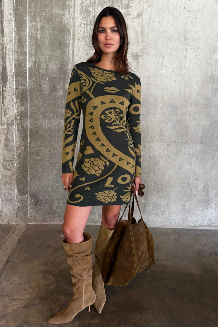 Olive Amara Knit Mini Dress with iconic hand, flower and eye motifs, styled with tall suede boots and a brown tote bag.