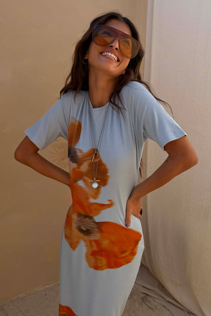 Orange Acetate Visor Sunglasses with 70s-inspired tinted lenses, worn by a smiling model in a blue floral dress.