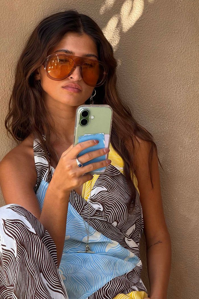 Orange Acetate Visor Sunglasses with 70s-inspired tinted lenses worn by a model in a wave print dress.