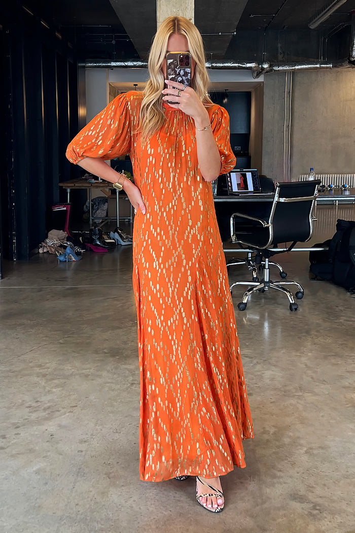 Orange jacquard Bibi maxi dress with gold diamond details and puff sleeves, shown in a studio mirror selfie.