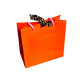 Vibrant orange NFD gift bag featuring pink rope handles, gold foil branding, and a signature leopard print tie.